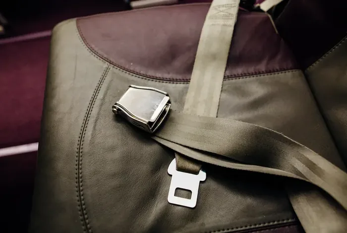 Lap belt with a metal lift-latch buckle fitted across a heavy-duty vehicle seat.
