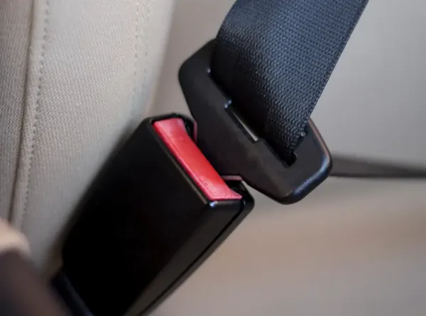 Seat belt buckle receiver with its red release button, latch plate engaged.