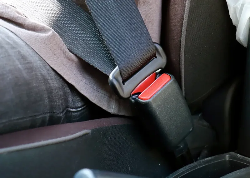 Seat belt fastened across a seated occupant in a car, with the latch plate engaged in the buckle.